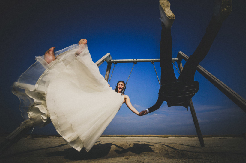 glueckliches hochzeitspaar schaukelt am strand von st. peter-ording, froschperspektive, farbfoto - hochzeitsfotograf st. peter-ording