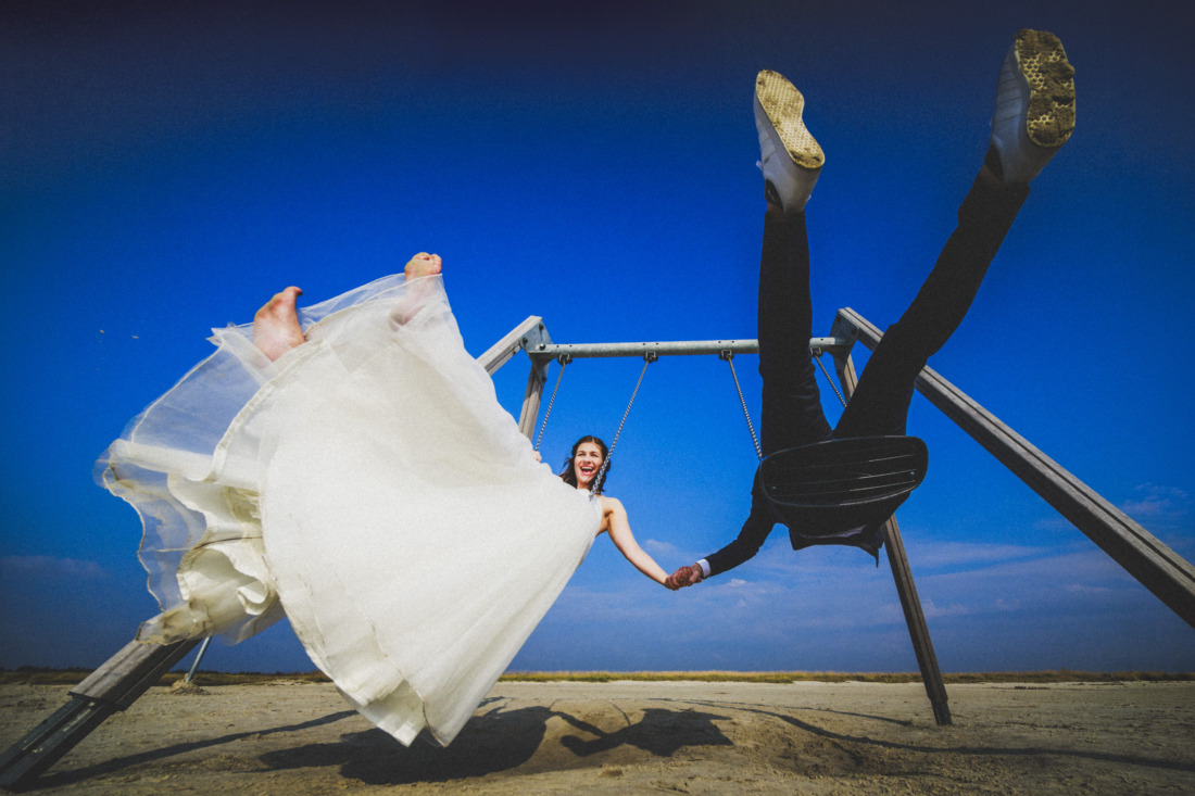 Brautpaar schaukelt Hand in Hand bei St. Peter Ording am Strand unter blauem Himmel - fotografiert von Rossi, Hochzeitsfotograf Gießen