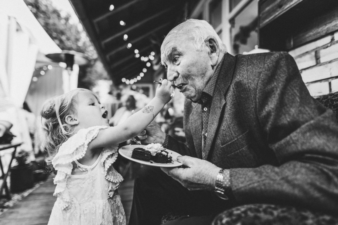 Kind füttert seinen Opa mit Kuchen auf einer Hochzeit - emotionaler Moment fotografiert von Rossi, Hochzeitsfotograf Gießen