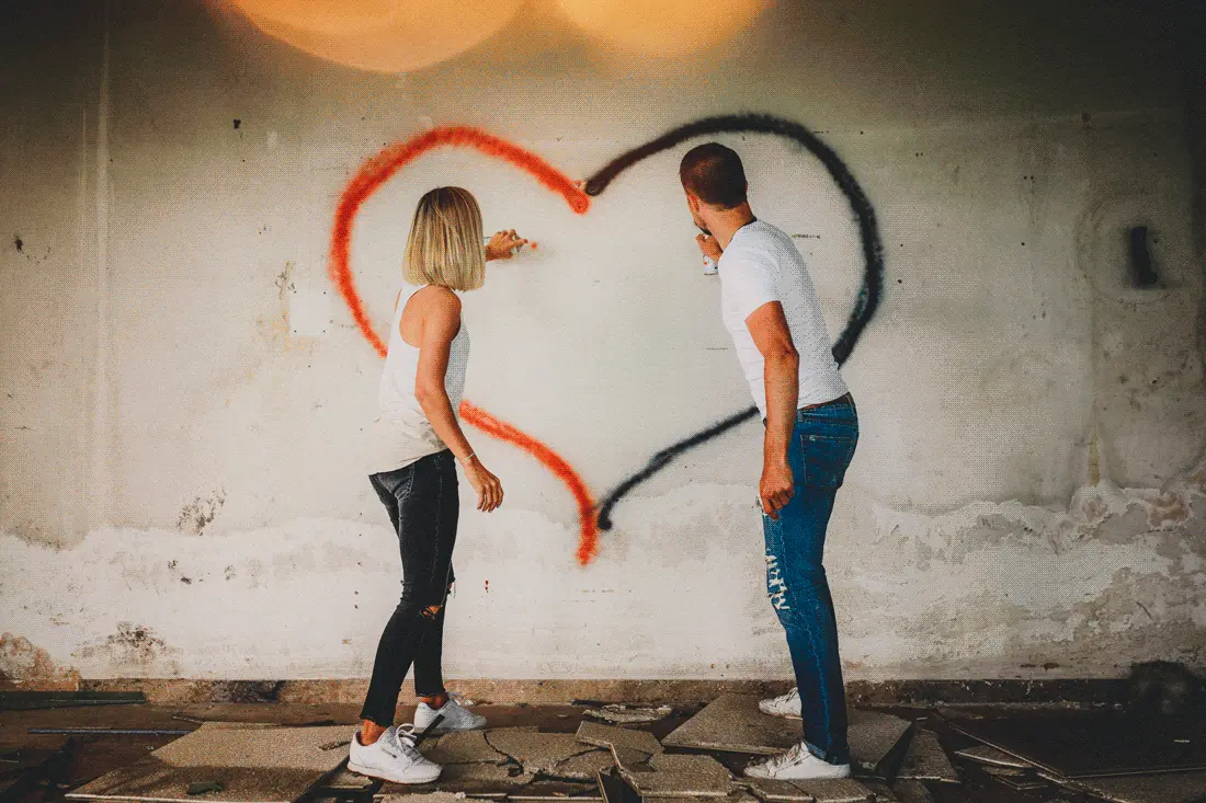 Kristina und Markus sprühen bei einem Verlobungsshooting im Lost Place ein großes Herz an eine alte Wand