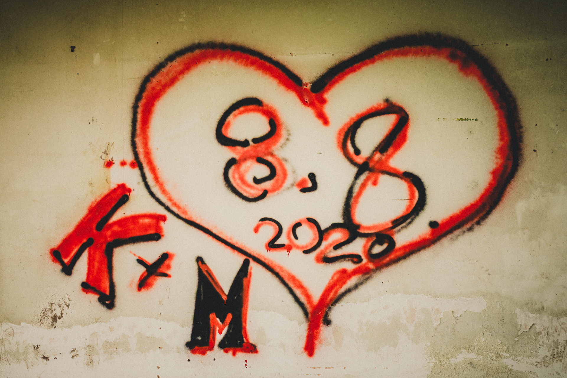 Rotes Herz-Graffiti mit den Initialen K und M an einer alten Wand in einem verlassenen Gebäude
