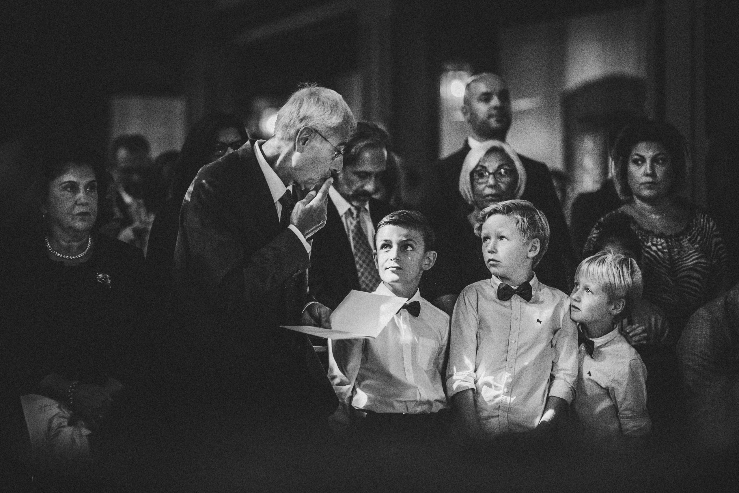 Kinder verfolgen aufmerksam die Trauung in der Kirche, während ein älterer Mann spricht - fotografiert von Hochzeitsfotograf Rossi