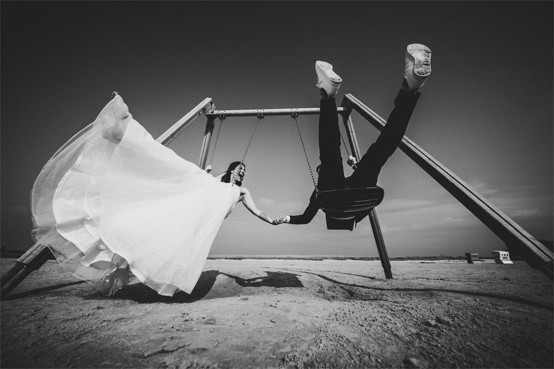 Hochzeitspaar schaukelt am Strand als bewegter Moment im Hochzeitsfotograf Portfolio von Rossi